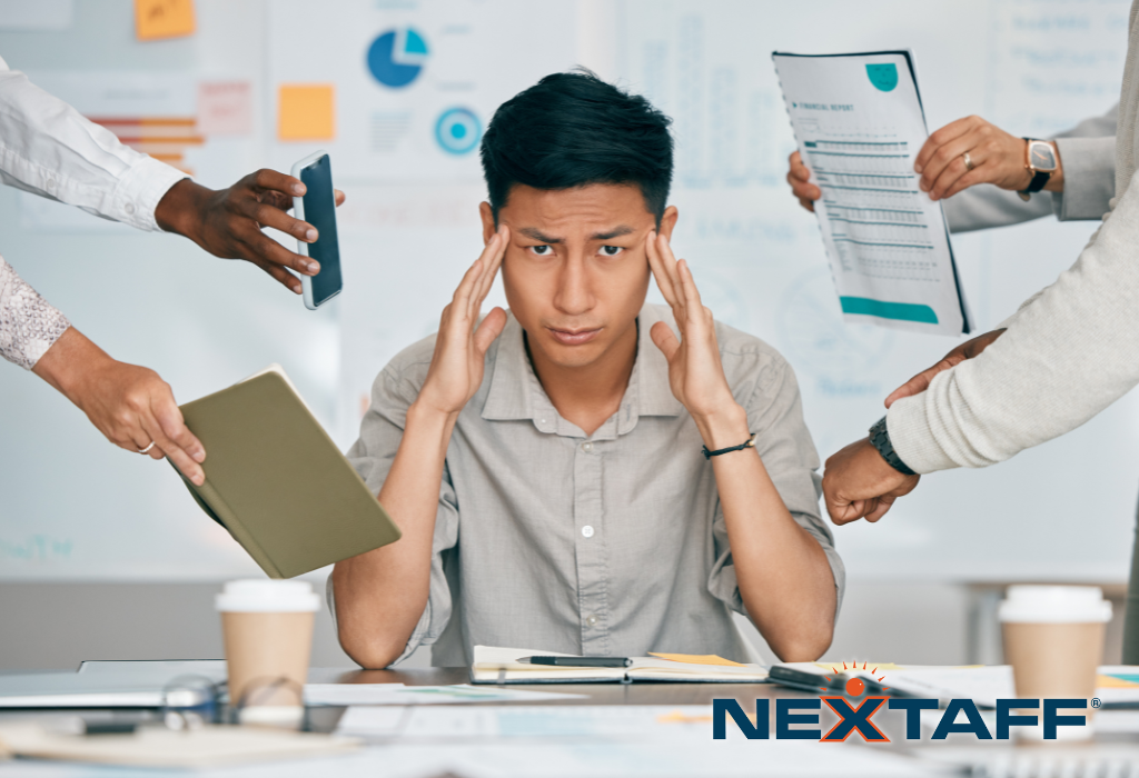 People trying to hand work related objects to a stressed staffing recruiter sitting at his desk.